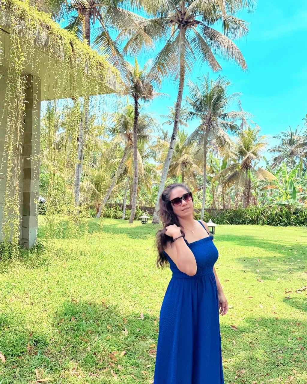 Rucci in a blue dress beneath Balinese palms